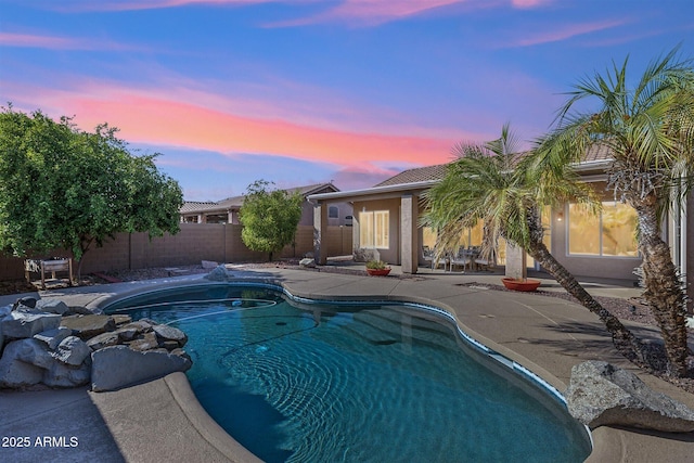 pool at dusk with a patio area