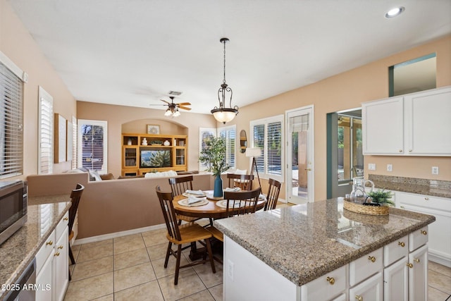 kitchen with white cabinets, decorative light fixtures, a kitchen island, and light stone counters