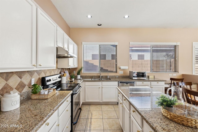 kitchen featuring light stone countertops, appliances with stainless steel finishes, sink, light tile patterned floors, and white cabinetry