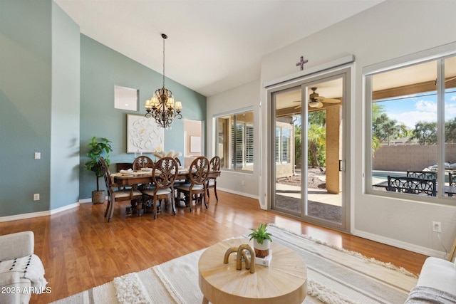 dining space with ceiling fan with notable chandelier, hardwood / wood-style flooring, and lofted ceiling