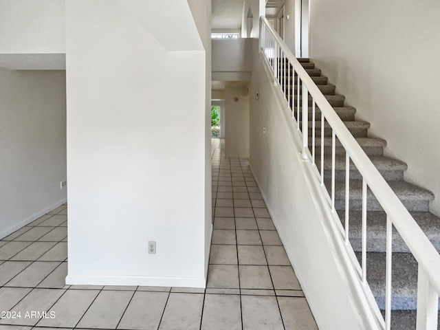 staircase featuring tile patterned flooring and a high ceiling