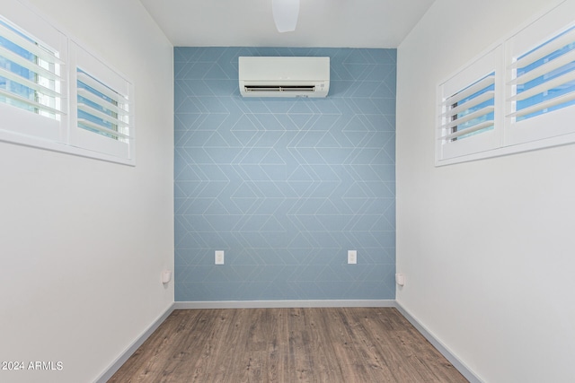 empty room with wood-type flooring, ceiling fan, and a wall mounted air conditioner