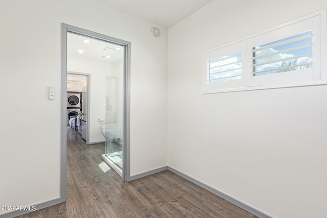 hall featuring stacked washer / dryer and wood-type flooring