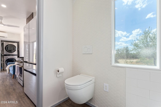 bathroom featuring ceiling fan, toilet, wood-type flooring, stacked washer / dryer, and a wall mounted air conditioner