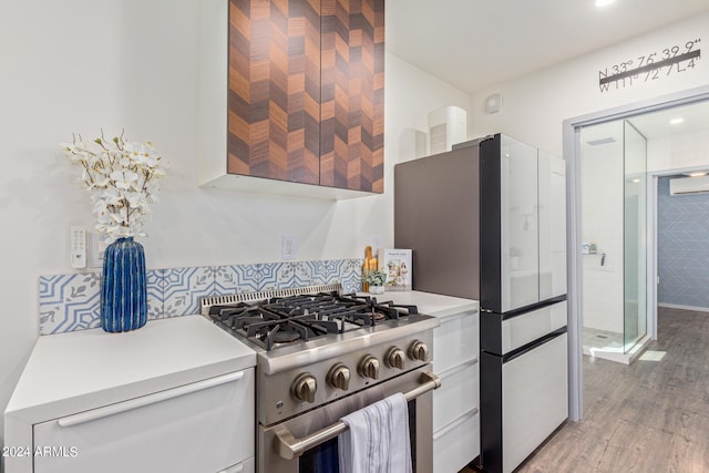 kitchen featuring wood-type flooring, white cabinets, high end stainless steel range, a wall mounted AC, and refrigerator