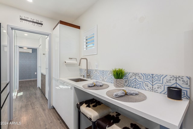 kitchen with tile walls, sink, a wall unit AC, and hardwood / wood-style flooring