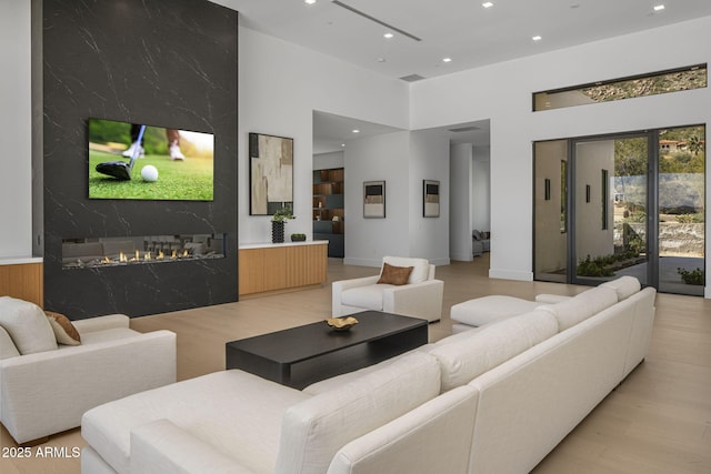 living room featuring a fireplace, light hardwood / wood-style flooring, and a high ceiling