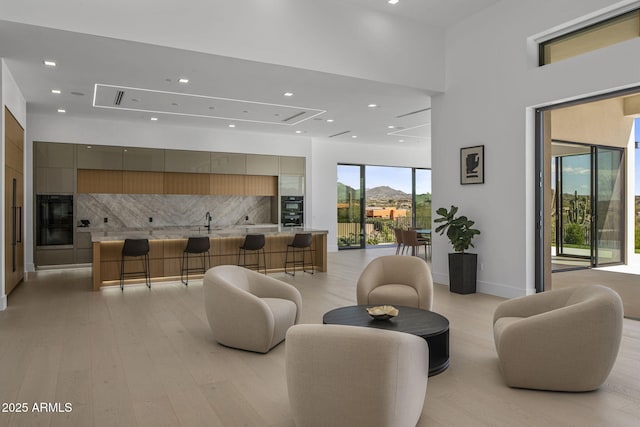 living room with sink, a high ceiling, and light wood-type flooring