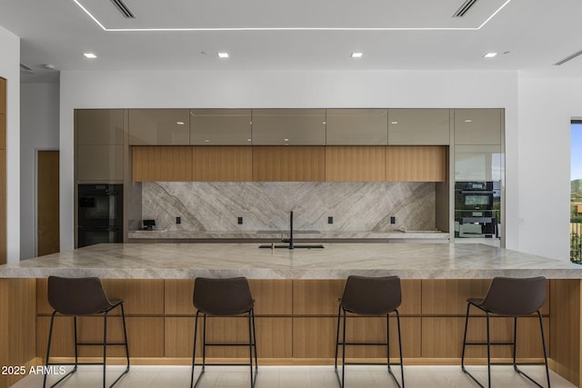 kitchen featuring sink, decorative backsplash, black double oven, and a breakfast bar