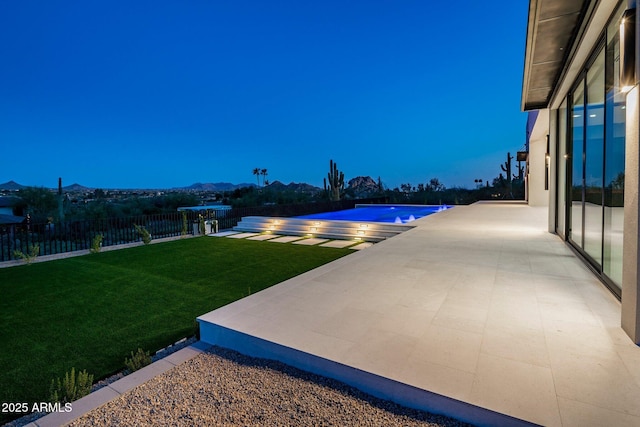 pool at dusk featuring a yard and a patio area