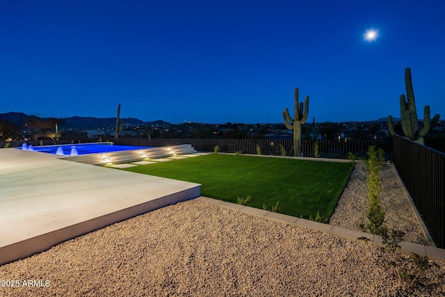 yard at twilight featuring a fenced in pool, a patio area, and a mountain view