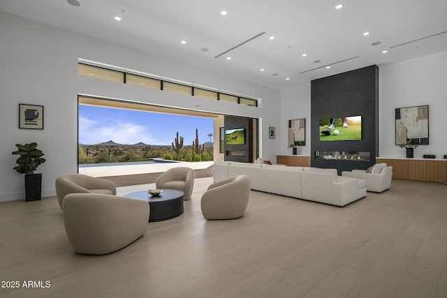 living room with a mountain view, a towering ceiling, a high end fireplace, and light hardwood / wood-style flooring