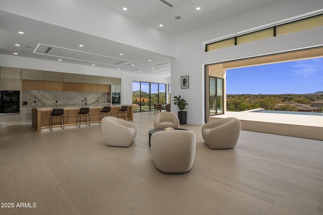 living room with a towering ceiling and light hardwood / wood-style floors