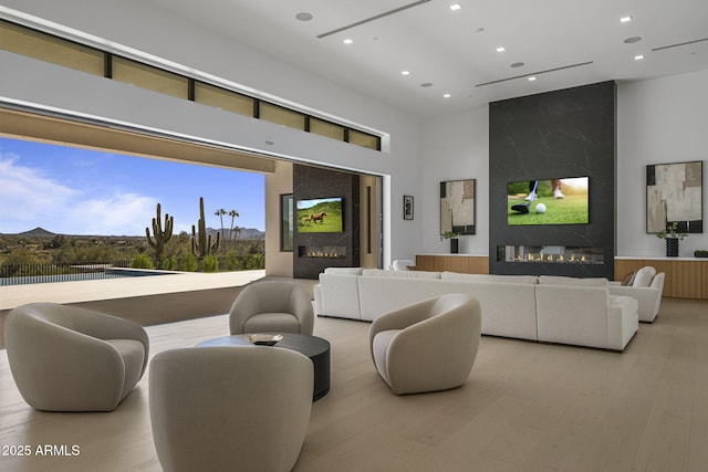 living room with a high ceiling, a fireplace, and light hardwood / wood-style flooring