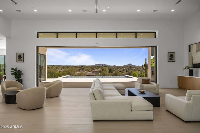 living room with a mountain view, a towering ceiling, and light hardwood / wood-style floors