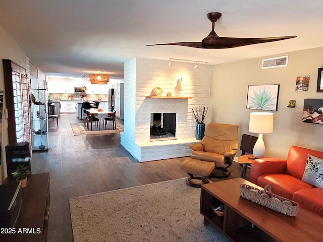 202 N Florence Ave, Litchfield Park, AZ 85340 - living area featuring rail lighting, dark wood-type flooring, ceiling fan, and a brick fireplace