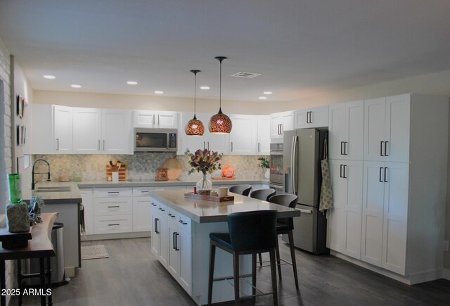 202 N Florence Ave, Litchfield Park, AZ 85340 - kitchen with appliances with stainless steel finishes, a sink, a kitchen bar, dark wood finished floors, and recessed lighting