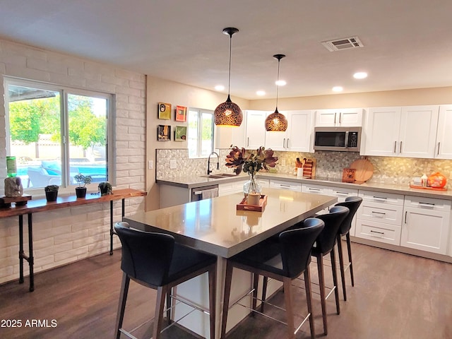 202 N Florence Ave, Litchfield Park, AZ 85340 - kitchen with appliances with stainless steel finishes, a sink, a breakfast bar, wood finished floors, and white cabinets