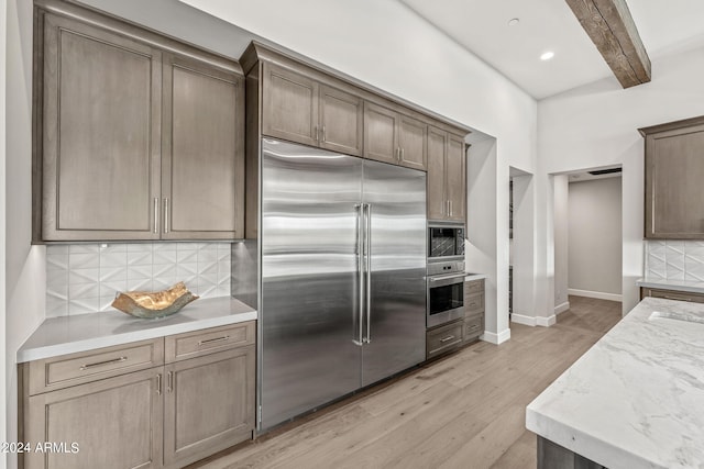 kitchen with built in appliances, light stone countertops, beam ceiling, light hardwood / wood-style flooring, and decorative backsplash