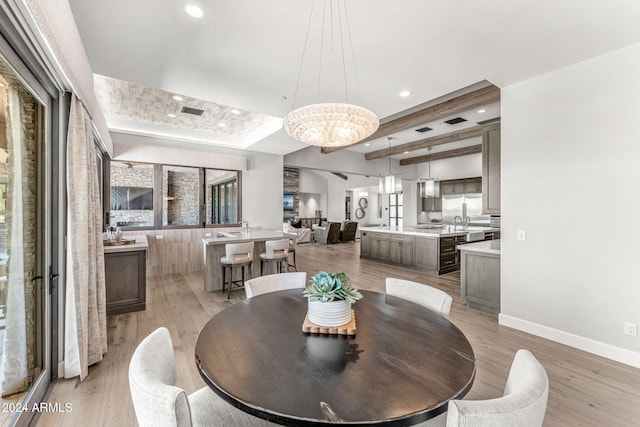 dining space featuring light wood-type flooring, a chandelier, and sink