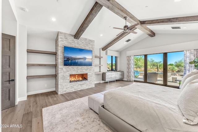 bedroom with a stone fireplace, vaulted ceiling with beams, hardwood / wood-style flooring, and ceiling fan