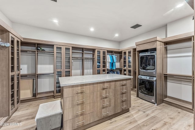 spacious closet featuring light wood-type flooring and stacked washer and dryer