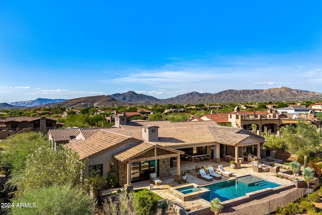 back of property featuring a patio, a mountain view, outdoor lounge area, and an in ground hot tub