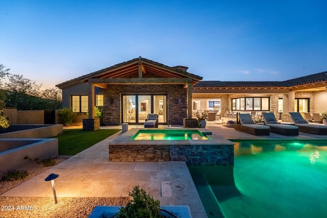 back house at dusk with a pool with hot tub, a patio, and an outdoor hangout area