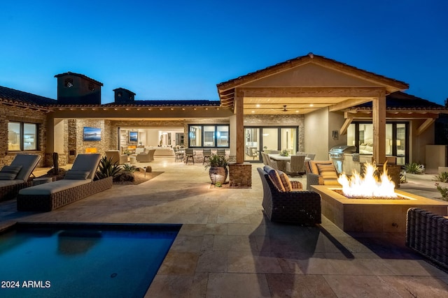 back house at dusk with ceiling fan, a patio, and an outdoor living space with a fire pit