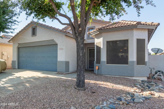 mediterranean / spanish-style home with a garage, concrete driveway, a tile roof, and stucco siding