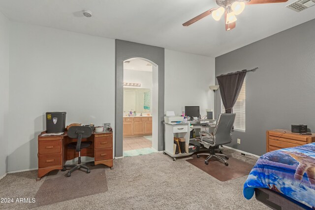 bedroom featuring ceiling fan, arched walkways, connected bathroom, light carpet, and visible vents