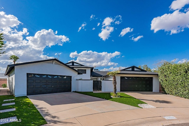 view of front of home with stucco siding, a garage, a fenced front yard, and concrete driveway