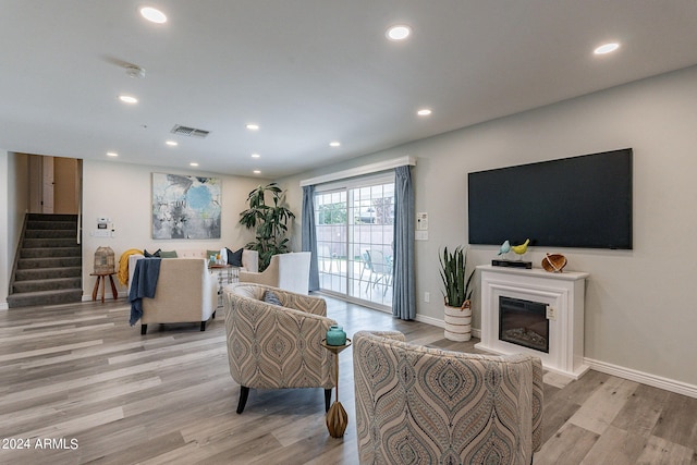living room featuring recessed lighting, light wood-style floors, stairway, and visible vents