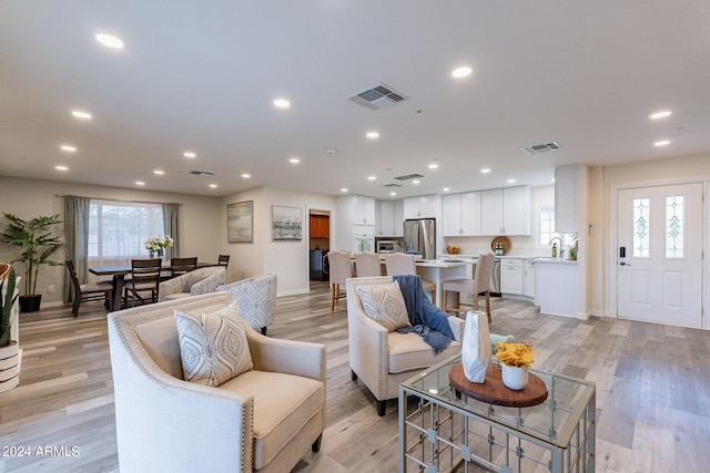 living room featuring light wood finished floors, baseboards, visible vents, and recessed lighting