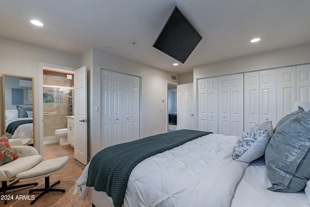 bedroom featuring light tile patterned flooring, two closets, and ensuite bath