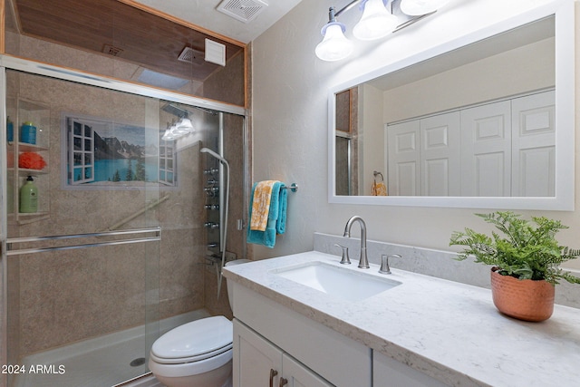 bathroom featuring a shower with door, vanity, and toilet