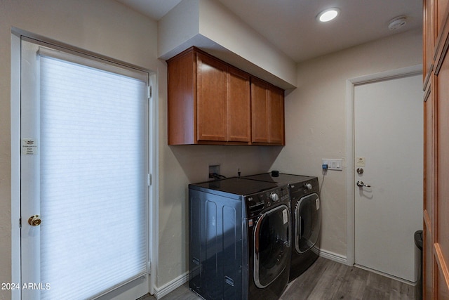 laundry room with light hardwood / wood-style floors, independent washer and dryer, and cabinets