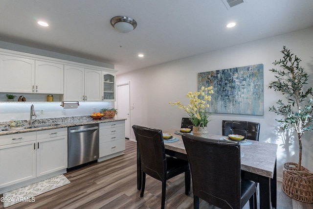 kitchen with dark wood-type flooring, sink, white cabinetry, light stone countertops, and stainless steel dishwasher