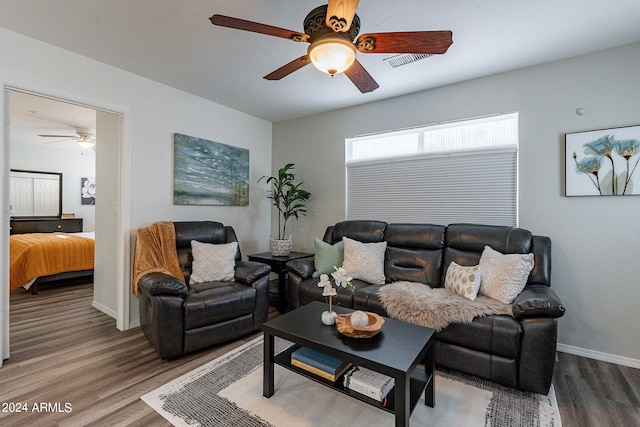 living area featuring baseboards, visible vents, wood finished floors, and a ceiling fan