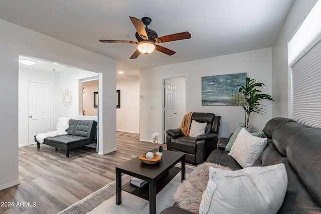 living area featuring baseboards, ceiling fan, and wood finished floors