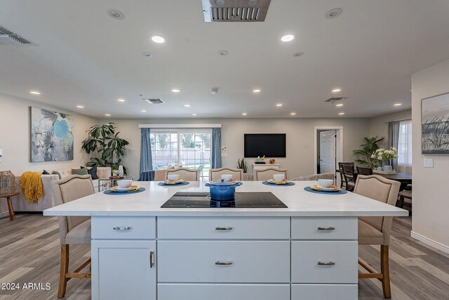 kitchen with open floor plan, black electric cooktop, a breakfast bar, and recessed lighting