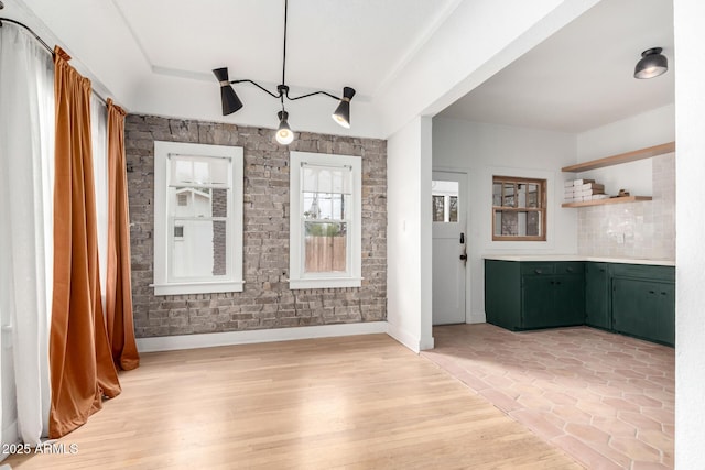 unfurnished dining area with light wood-type flooring and a raised ceiling