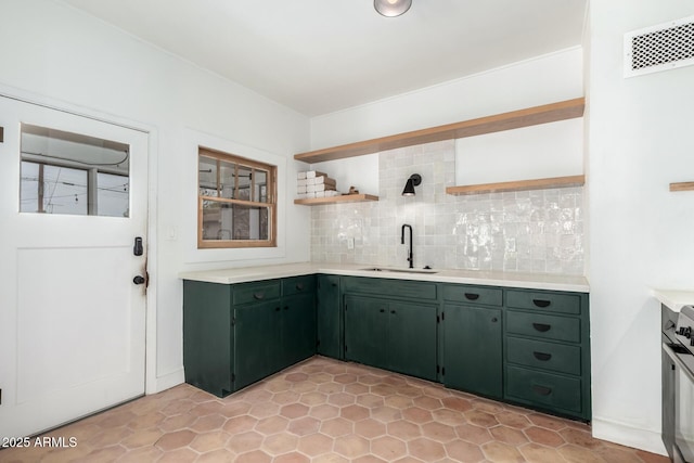 kitchen with green cabinets, sink, decorative backsplash, and stove