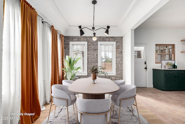 dining space featuring light wood-type flooring and a raised ceiling