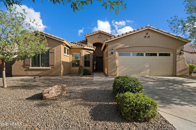 mediterranean / spanish house featuring an attached garage, stucco siding, concrete driveway, and a tile roof