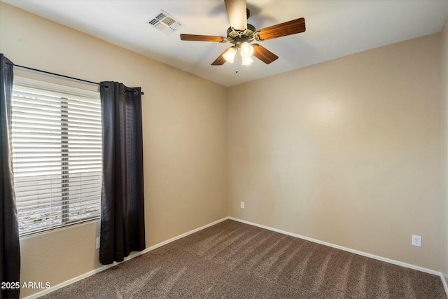 unfurnished room featuring dark carpet, a ceiling fan, a wealth of natural light, and visible vents