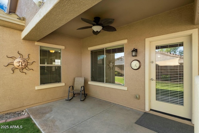 doorway to property with a patio, a ceiling fan, and stucco siding
