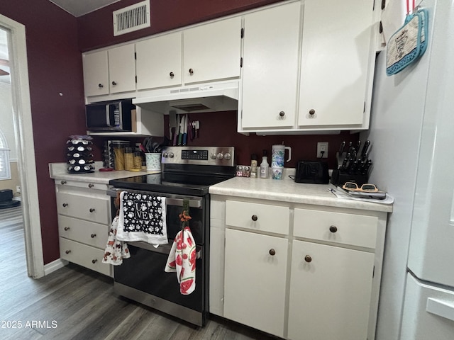 kitchen with under cabinet range hood, visible vents, white cabinetry, light countertops, and stainless steel range with electric stovetop