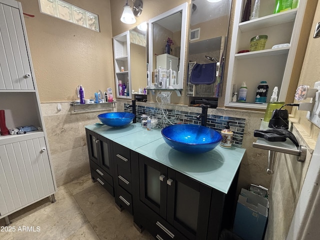 full bathroom featuring a wainscoted wall, double vanity, a sink, and visible vents