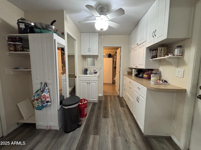 kitchen with dark wood finished floors, light countertops, white cabinetry, open shelves, and a sink